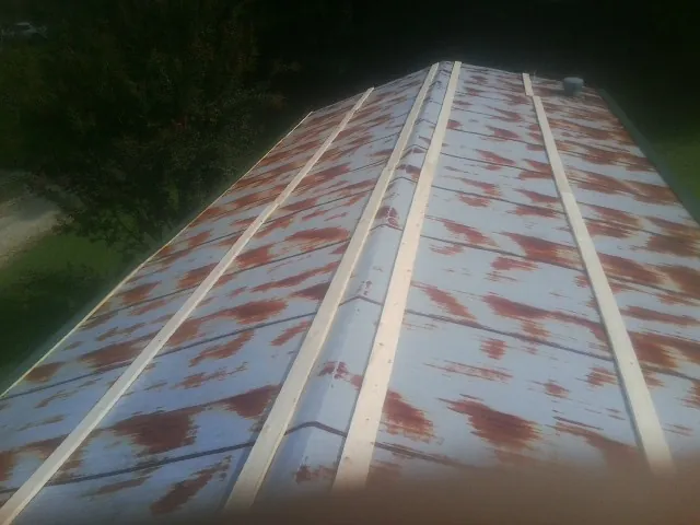 Rusted metal roof panels with new wood purlins before replacement — Storm Damage Roof Repair in Johnson by Roofing Brothers