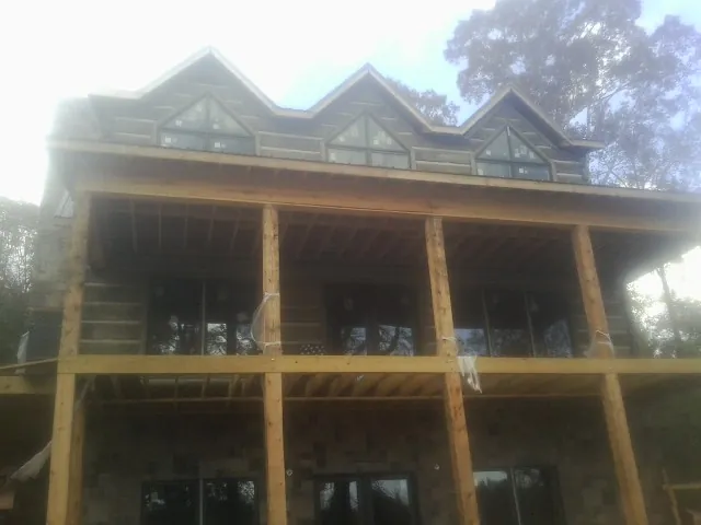 Dormers and porch framing on a large log home under construction — Roof Coating work by our crew in Johnson