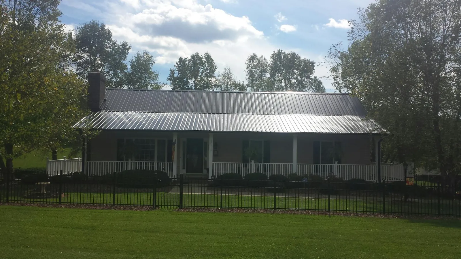 Gray metal roof on a brick ranch with a full width front porch — Gutter Guard Installation work by our crew in Johnson