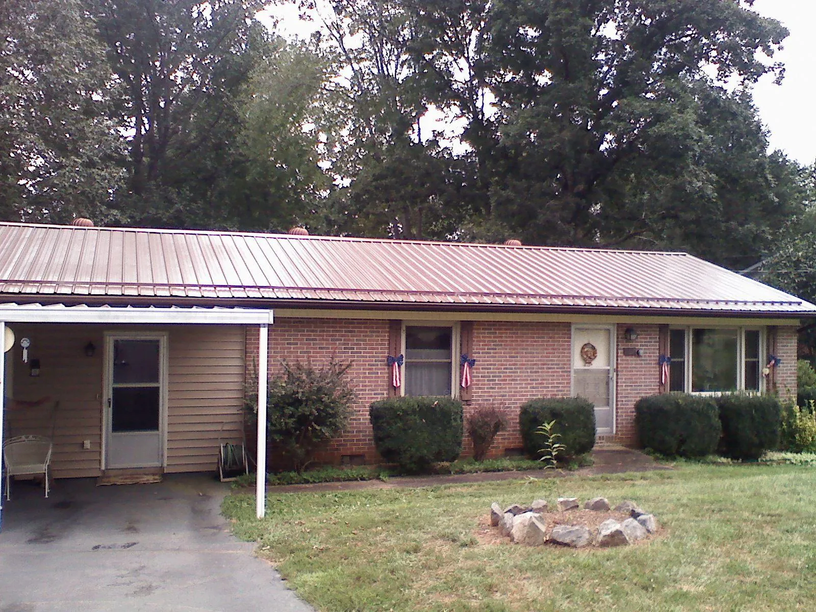 Bronze metal roof and carport on a brick ranch home — Roof Repair work by our crew in Johnson